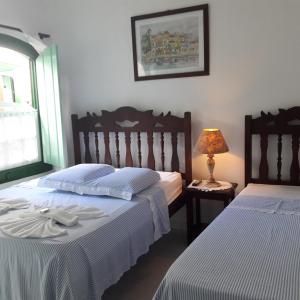 a bedroom with two beds and a lamp on a table at Pousada Sonho Meu in Paraty