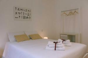 a bedroom with a white bed with towels on it at Siglas & Runas in Póvoa de Varzim