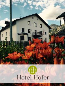 un cartel de hotel más caliente con flores naranjas frente a una casa en Hotel Hofer, en San Valentino alla Muta