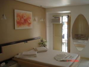 sypialnia z łóżkiem i lustrem w obiekcie Hotel Don Juan w mieście Salvador