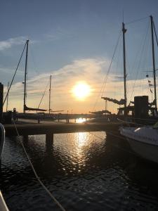 a sunset over a dock with boats in the water at Villa Böck am Strand FeWo 8 in Glowe +13 photos