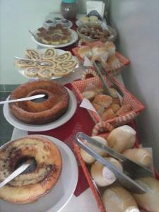 a table full of different types of pastries on plates at Pousada Beija Flor in Cambuci +8 photos