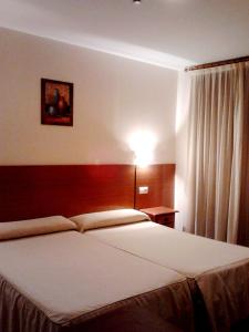 a bedroom with a large white bed and a lamp at Eurico in Toledo