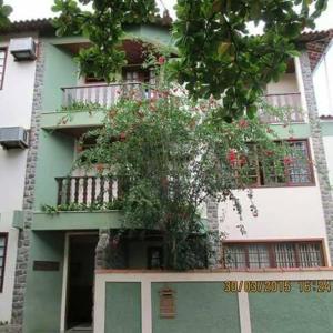 Pousada Beija Flor في Cambuci: مبنى اخضر وابيض وامامه شجرة