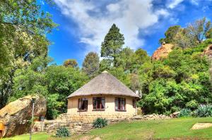 a small house with a thatched roof in a field at Little Rock Resort in Ladybrand