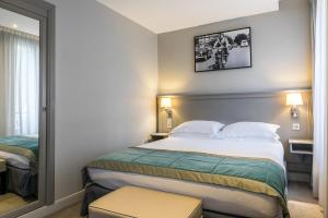 - une chambre d'hôtel avec un lit et un miroir dans l'établissement Best Western Montcalm, à Paris