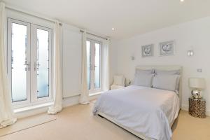 a white bedroom with a bed and large windows at Tower Bridge Lux-Townhouse in London