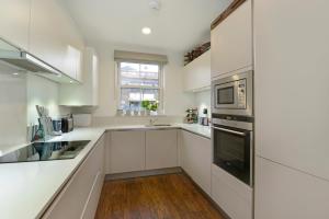 eine weiße Küche mit einer Spüle und einer Mikrowelle in der Unterkunft Tower Bridge Lux-Townhouse in London