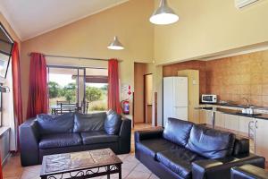 a living room with two leather couches and a kitchen at Monateng Safari Lodge in Wallmannstal