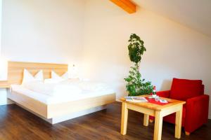 リーデンにあるSeehotel und Appartements Schnöllerのベッドと赤い椅子のある寝室