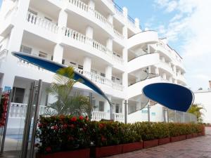 Hotel Zamba في جيراردو: مبنى أبيض فيه مظلات زرقاء أمامه
