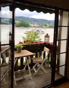 eine Veranda mit einem Tisch und Stühlen sowie Blick auf das Wasser in der Unterkunft Villa Christina in Kamp-Bornhofen