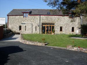 a stone house with a lawn in front of it at The Barn B&B in Margam