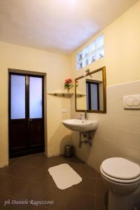 uma casa de banho com um WC, um lavatório e um espelho. em La Corte di Alzo em Pella