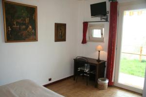 a bedroom with a bed and a desk and a television at B&B Maggiora 131 in Acqui Terme