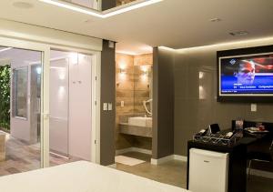 a bedroom with a tv on the wall and a bathroom at Motel Quo in São Paulo +47 photos