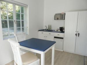 a kitchen with a blue table and white cabinets at The Plantation in Port Elizabeth