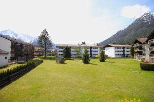 um grande quintal relvado em frente a um edifício em Lindenschlösschen & Schlossgarten em Garmisch-Partenkirchen