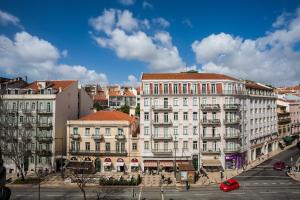 un grande edificio bianco su una strada di città con le auto di Baixa most beautiful and luminous 3 BDR flat a Lisbona