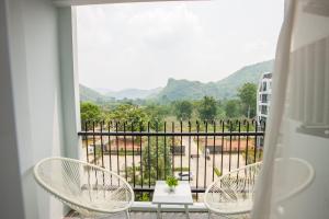 a balcony with two chairs and a view of mountains at Courtyard Khaoyai by Paka in Mu Si