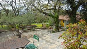 eine Terrasse mit einem Holztisch, Stühlen und Bäumen in der Unterkunft Chambres d'hôtes de la gardy in Eyragues