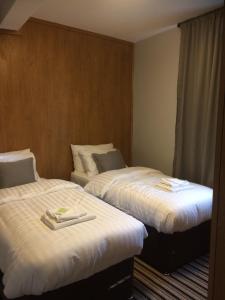 a hotel room with two beds with white sheets at TW4 Apartments – Hounslow in Hounslow
