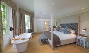 Schlafzimmer mit einem Bett, einer Badewanne und einer Badewanne in der Unterkunft Stoke Place- Part of the Cairn Collection in Slough