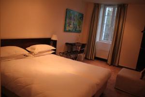 a bedroom with a white bed and a window at Hotel La Beauze in Aubusson