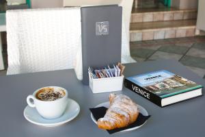 una tazza di caffè e un cornetto su un tavolo di Villa Serena a Lido di Jesolo