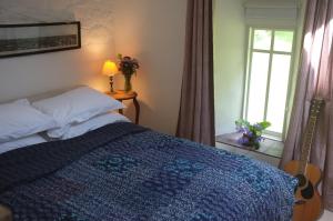 Schlafzimmer mit einem Bett mit Gitarre in der Unterkunft Bake House Cottage in Shepton Mallet