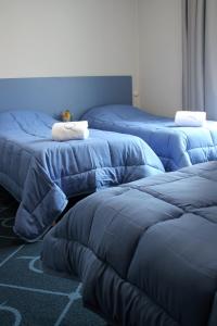 een kamer met drie bedden met blauwe lakens bij Le Petit Majestic in Lourdes