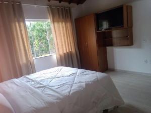 1 dormitorio con 1 cama y TV de pantalla plana en Apartamento no Centro Búzios, en Búzios
