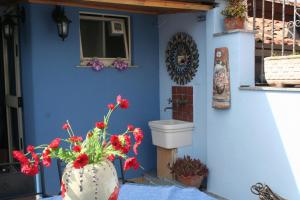 een blauwe muur met een toilet en bloemen in een vaas bij Casa vacanze Aloha in Giardini Naxos