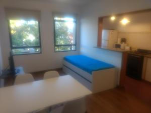 Habitación pequeña con cama azul y cocina en Departamento 37 en La Plata