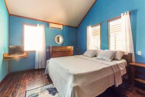 sypialnia z niebieskimi ścianami i łóżkiem z białą pościelą w obiekcie Casa Jessita w Caye Caulker