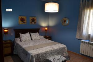 a bedroom with a bed and a blue wall at Apartamentos Rurales Natura in Torrejón el Rubio