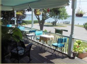 a porch with chairs and tables and an umbrella at The Stirling House Waterfront Inn Greenport in Greenport