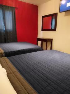 1 dormitorio con 2 camas y pared roja en Posada " El Jardín", en Xilitla