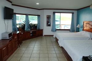 a hotel room with two beds and a television at Fish Hook Marina Hotel in Golfito