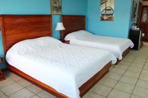 two beds in a room with blue walls at Fish Hook Marina Hotel in Golfito