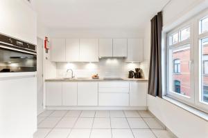 cocina con armarios blancos y ventana grande en Kalbergstay 3 work stay Apartment, en Oostrozebeke