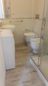 a bathroom with two toilets and two sinks and a shower at Appartamento Madda in La Maddalena