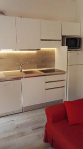 a kitchen with white cabinets and a red couch at Appartamento Madda in La Maddalena