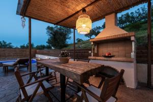 a patio with a wooden table and a fireplace at Casa Di Terra in Pigadhákia