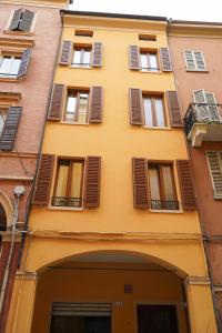 a yellow building with brown shuttered windows at Emilia Studios in Modena