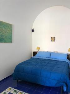 a bedroom with a blue bed in a white room at La Casa del Giudice in Atrani