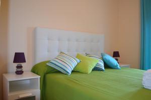a green bed with blue and yellow pillows on it at Apartamentos Solmares in Isla Canela