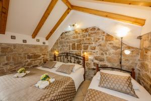 two beds in a room with a stone wall at Villa Spaladium in Split