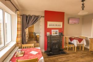 a living room with a red wall and a table and a fireplace at The Pipers Rest in Doolin