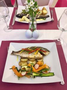two plates of fish and vegetables on a table at The Capital Boutique B&B in Peniche